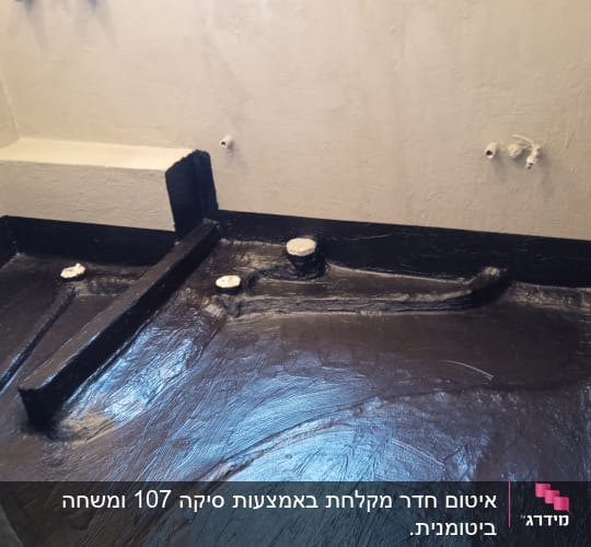 רצפה אטומה עם חומר איטום שחור וצינורות חשופים